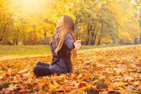 2 Young woman sitting on a fallen autumn leaves in a park photo