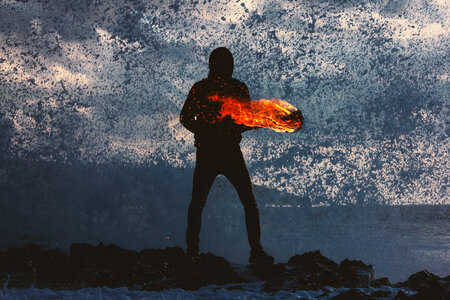 Mysterious Person Holding Fire Torch against Splashing Waves photo