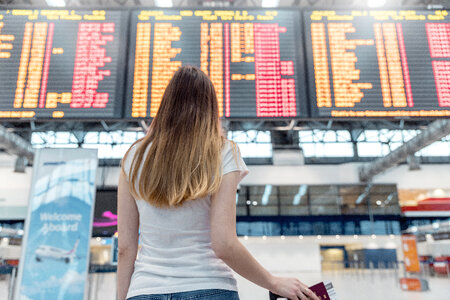 Young woman standing against flight scoreboard in airport photo