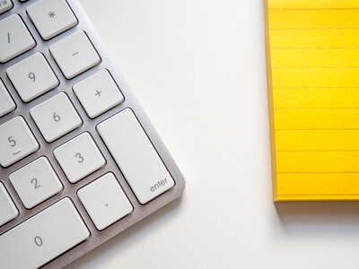 Keyboard and Yellow Notepad on a White Desk photo
