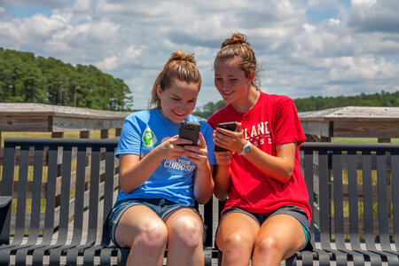 Students sittting on bench sharing cell phone pictures-1