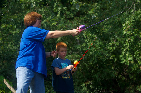 Service employee instructing her son on how to cast his line