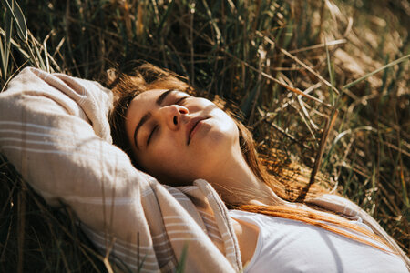 Young Woman Relaxing Lying on the Grass with Closed Eyes Enjoying Sunlight photo