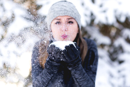 Young Woman Blowing Snow toward Camera Outdoors photo