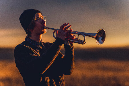 Young Man with Black Hat Playing a Trumpet at Sunset photo