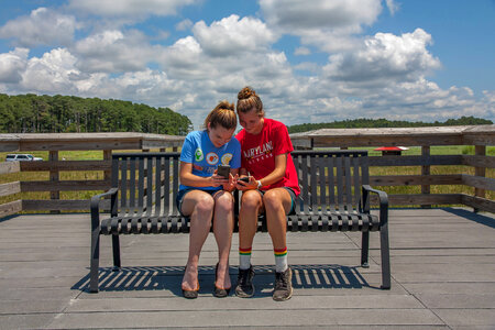 Students sittting on bench sharing cell phone pictures-6