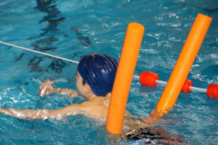 Funny little boy swims in a pool in an orange life preserver photo