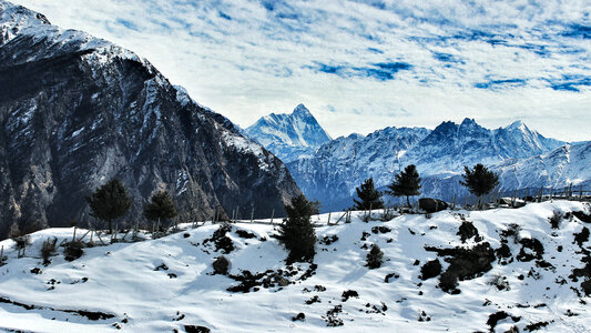 Snow-capped mountains with clouds overhead in Auli, India photo