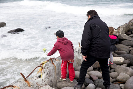 Children and elder placing flowers in ocean