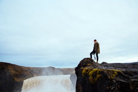 Hiker On Cliff By Waterfall photo