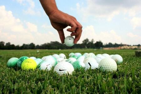 Hands placing golf balls photo