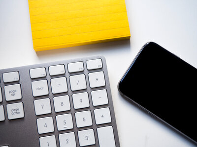 Keyboard, Phone, and Yellow Note on White Desk photo