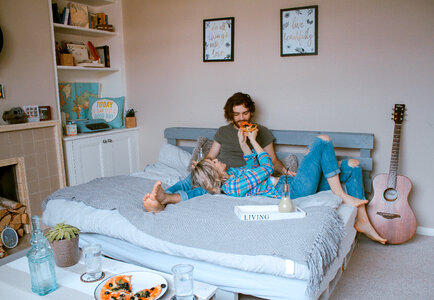 Couple Feeding each other in Bed with Pizza photo