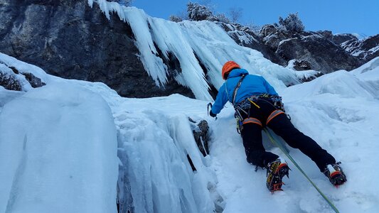 A young climber climbs on ice climbing