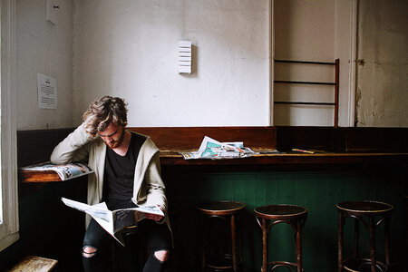 Young Bearded Man Reading a Newspaper in a Cafe photo
