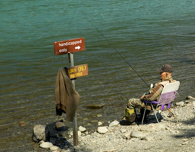 Fisherman sitting by handicapped sign in Alaska