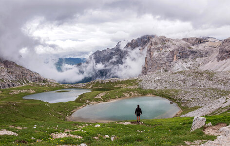 Male hiker in the Italian Dolomites Mountains overlooking a lake photo