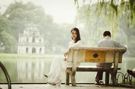 Romantic young couple sitting on park bench by lake