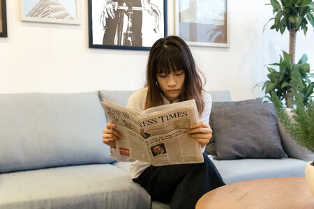 A pretty asian business woman reading the newspaper photo