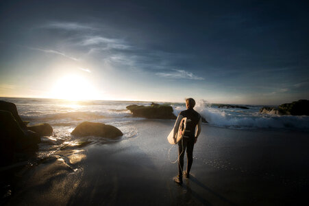 Surfer Walking on the Beach at Sunset photo