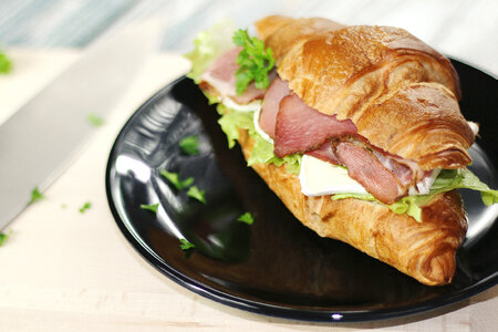 Fresh sandwich with ham and vegetables on the black plate photo