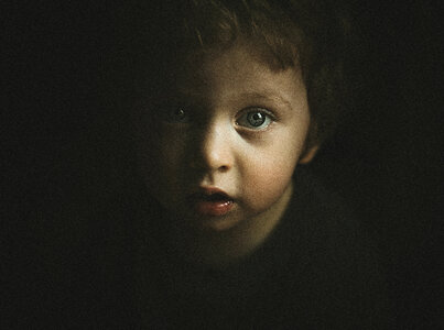 Face of Little Boy Emerging from Darkness photo
