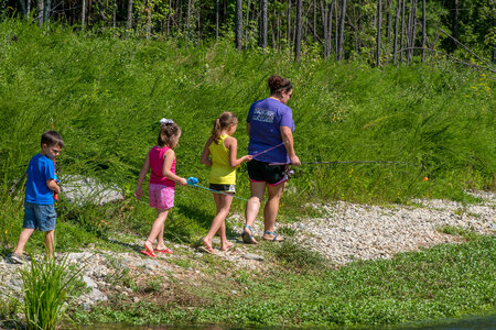 Family walks along stream with fishing rods