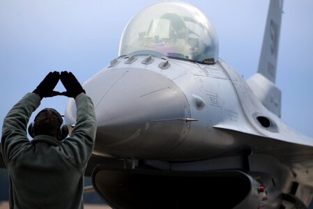An Airman marshals an F-16 Fighting Falcon photo