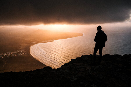 Man Silhouette High on Cliff at Sunset photo