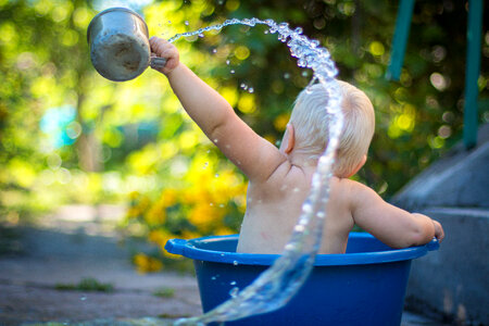 Baby Boy Playing Outside in Blue Bowl with Water photo