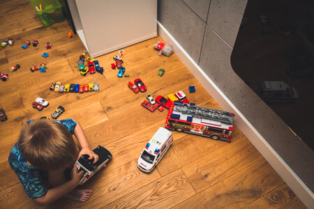 Little Boy Playing with Lots of Colorful Car Toys Indoor