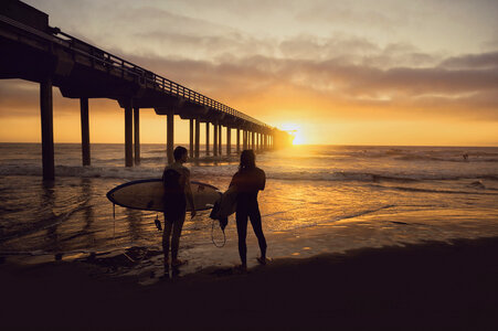Silhouette of Two Surfers Carrying Their Surfboards on Sunset photo
