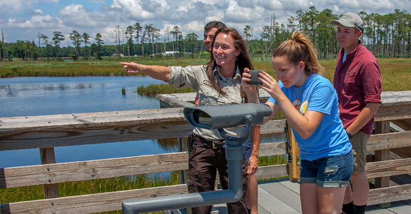 Girl takes cell phone picture of wetland with FWS employee pointing-1