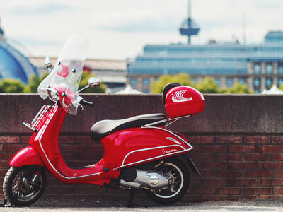 Red Vespa Scooter Parked by the Small Brick Wall photo