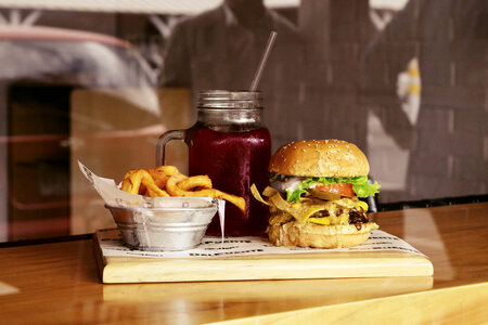 Tasty Burger with Fries and Beverage on Wooden Table photo