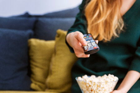 Young girl with TV remote and a popcorn at home photo