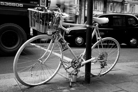 Black and White photo of Bicycle leaning on post photo