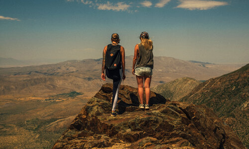 Two Girls Standing Back on Top of a Mountain Enjoying the View photo