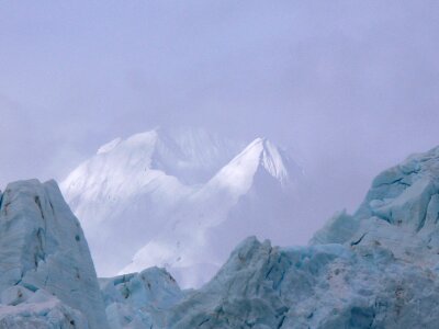 Mountains rise through the clouds above a glacier photo