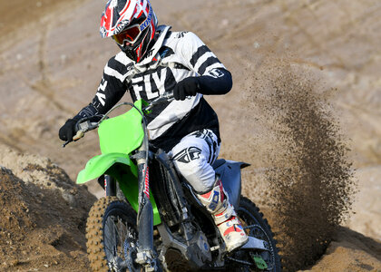 Motocross rider accelerating in curve in dirt track