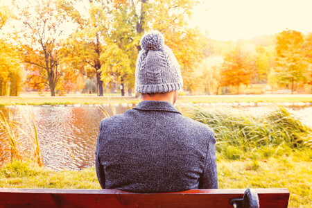 A young man sitting on a bench at the park in autumn photo
