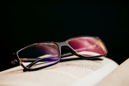 Open Book with Glasses on Black Background photo