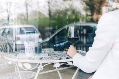 Woman drinking red wine behind a window photo