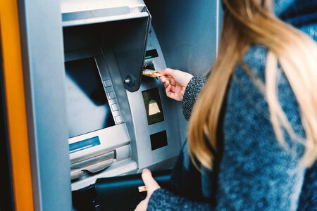Young woman withdrawing money from credit card at ATM photo