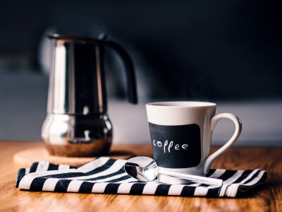 Cup of coffee and pot with blur coffee shop background photo