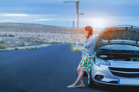 Young woman near broken car calling for help photo