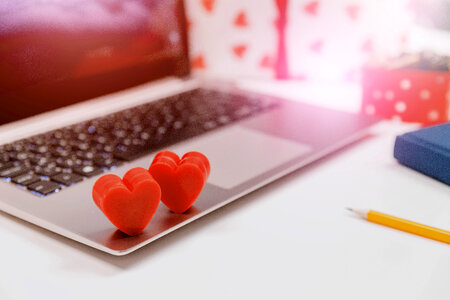 Couple red hearts on laptop on white table in office. Online dating. photo