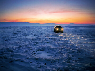 Car on an Frozen Lake Baikal at Sunset photo