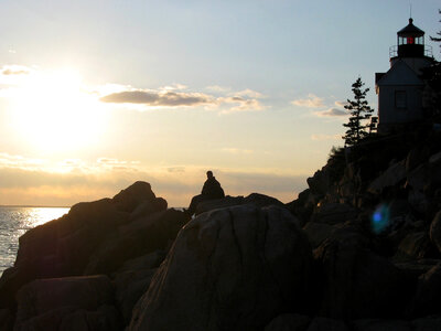 Guy watching sunset on the rocks at Acadia National Park, Maine photo