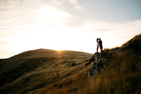 Young Couple Kissing on the Rock at Sunset photo